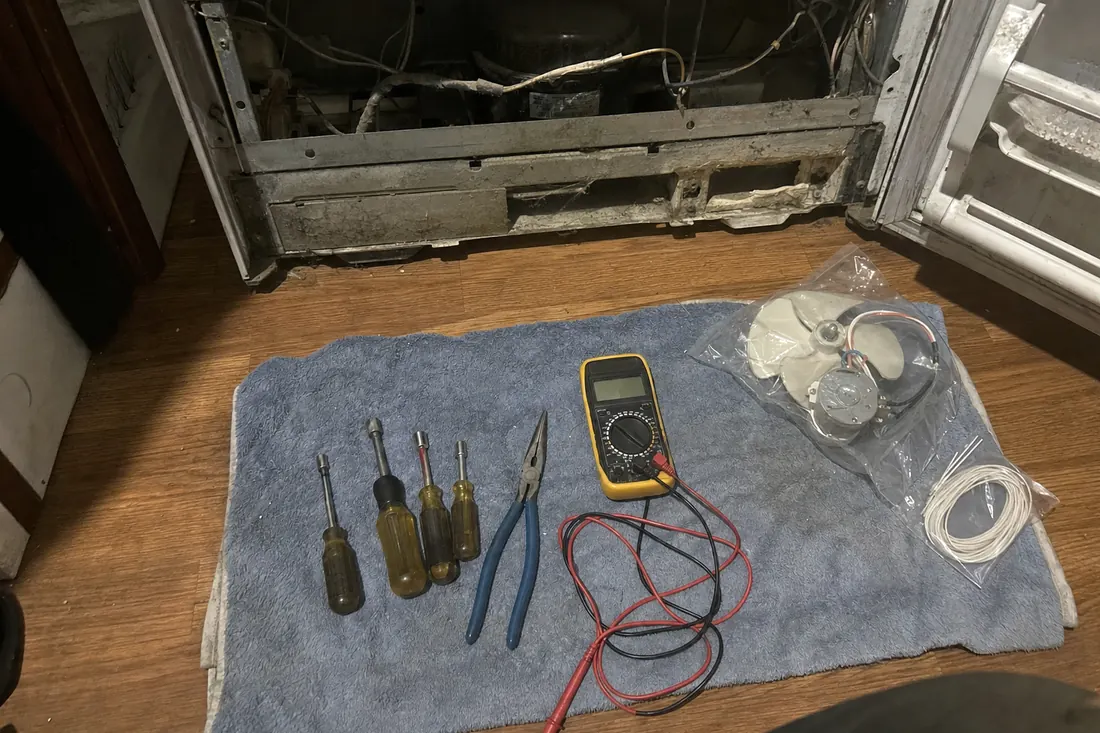 Flat-lay of nut drivers, pliers, a multimeter and a bagged fan motor on a towel, the bagged fan motor in frame - Sub-Zero Repair Across the First Coast