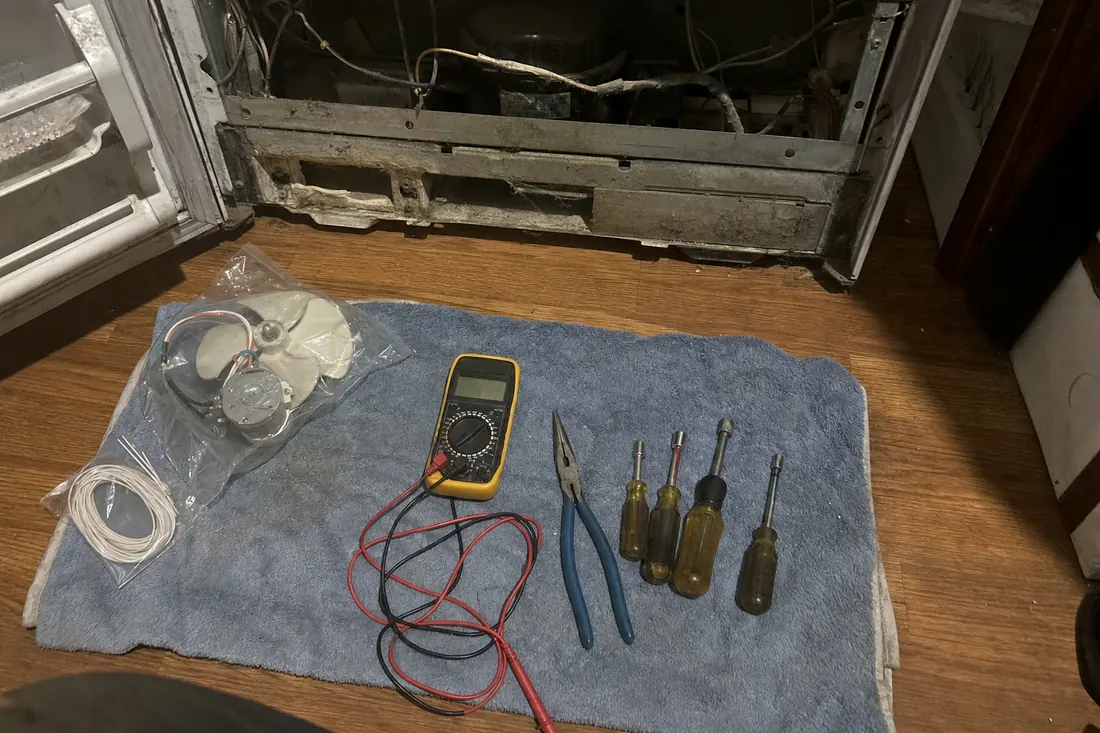 Flat-lay of nut drivers, pliers, a multimeter and a bagged fan motor on a towel, the nut drivers in frame - Contact and booking