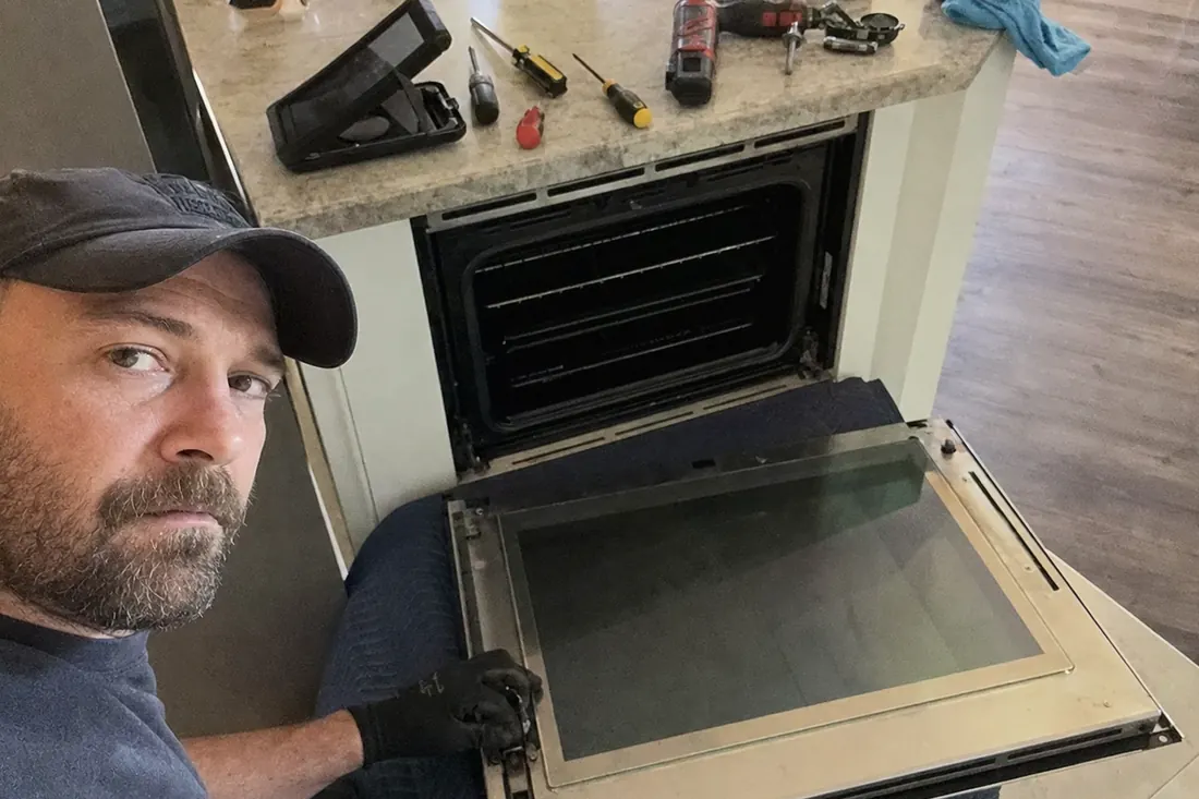 A wall oven door off its hinges on a moving blanket, hinge mechanism exposed, the hinge arm visible in the picture - Fitting Built-Ins Into Pre-War First Coast Kitchens